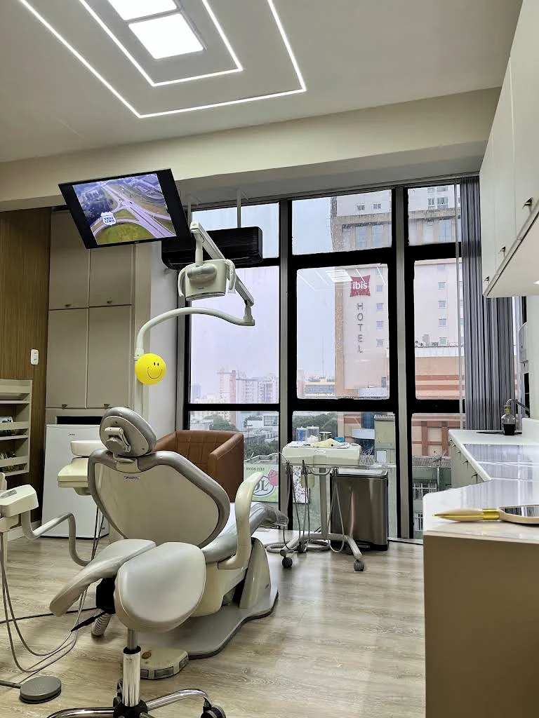 Cadeira odontológica vista de outro ângulo, diante de janelas amplas com vista para o Centro.